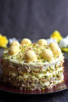 a cake with white frosting and pistachios on top sitting on a plate