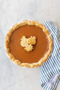 there is a pie on the table with a blue and white napkin next to it