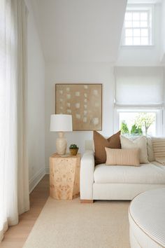 a living room filled with furniture and a large painting on the wall above it's windows