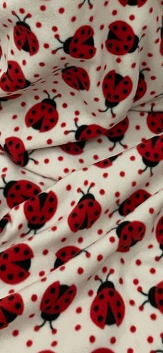 a red and black ladybug print fabric with white polka dots on the bottom