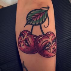 a woman's arm with three cherries on it and a green leaf in the middle