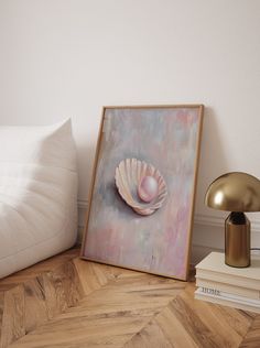 a painting is on the floor next to a lamp and books in a room with white walls