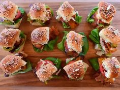 many small sandwiches are arranged on a wooden board