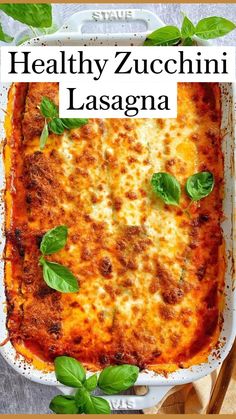 a casserole dish with basil leaves on top and the words healthy zucchini lasagna above it