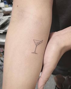 a woman's arm with a small martini tattoo on it