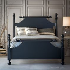 a black bed with two pillows sitting on top of it next to a night stand