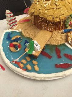 a cake that is shaped like a house on top of a lake with fish in it