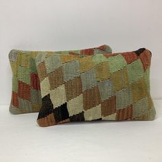 two multicolored pillows sitting next to each other on a white surface with no one in the photo