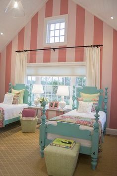 two beds in a room with pink and white striped walls, windows, and rugs on the floor