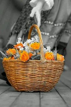 a basket filled with flowers sitting on top of a table next to a woman's face