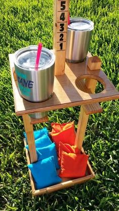 a wooden stand with two cups on it and a ruler in the grass behind it