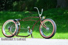 an old fashioned bicycle is parked on the side of the road in front of some grass