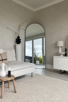 a living room filled with furniture and a large mirror on the wall above it's doorway