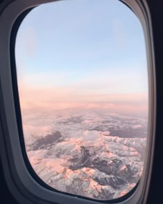 an airplane window looking out at the snow covered mountains