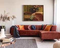 a living room with a couch, coffee table and vase on the floor in front of it