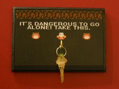 a key chain hanging from the side of a red wall next to a sign that says it's dangerous to go alone take this