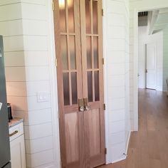 the interior of a house with white walls and wood floors, an open door leading to a kitchen