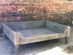 an old wooden bed frame sitting in front of a brick wall on the side of a building