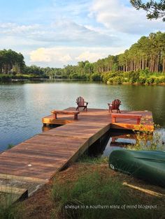 two empty chairs on a dock near the water and canoes in the foreground