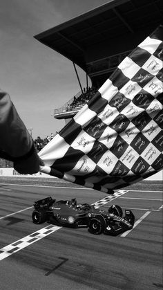 a person holding up a checkered flag next to a race car on the track