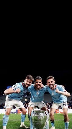 three soccer players pose for a photo with the trophy