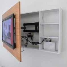 a tv mounted to the side of a white wall next to a wooden framed object