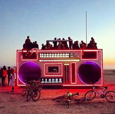 a group of people sitting on top of a boom box with bicycles parked in front of it