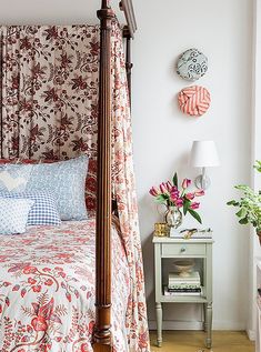 a canopy bed in a bedroom with floral bedspread and pillows on top of it