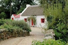 a white house with a red door surrounded by greenery