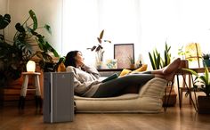 a woman sitting on a couch with her feet up in front of the air conditioner