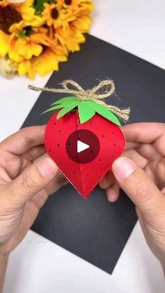 someone is holding a paper strawberry ornament