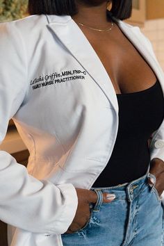 a woman in jeans and a white jacket is posing for the camera with her hands on her hips