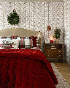 a bedroom with red bedding and christmas decorations on the headboard, nightstands and chest of drawers