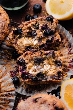 blueberry muffins cut in half on top of paper next to sliced lemons