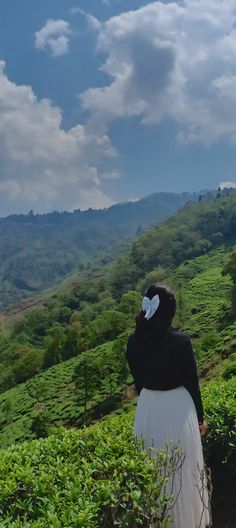 a woman standing on top of a lush green hillside