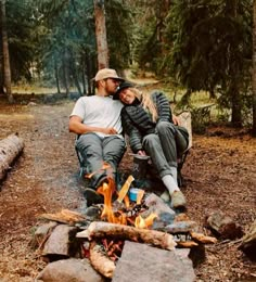 two people sitting next to each other near a campfire