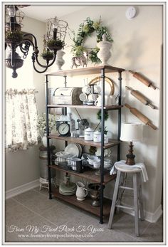 a shelf filled with lots of dishes next to a wall mounted chandelier in a living room