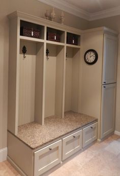 a clock is on the wall above some white cabinets with drawers and bins in front of them