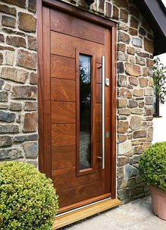 a wooden door sitting on the side of a stone building next to potted plants