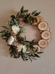 a wreath made out of wood slices with white flowers and greenery on the front