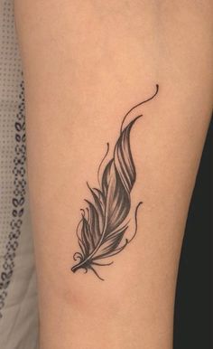 a black and white feather tattoo on the leg