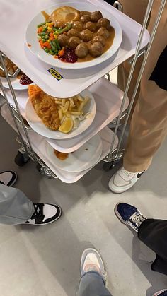 three tiered trays with food on top of each other in front of people's feet