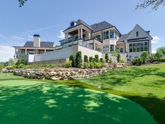 a large house on the side of a golf course with a green in front of it