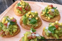 small appetizers with guacamole and other toppings on a wooden tray