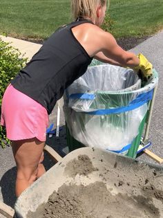 a woman is pushing a wheelbarrow filled with sand