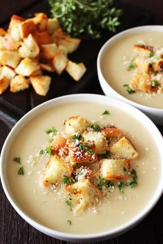 two white bowls filled with soup and garnished with parmesan cheese