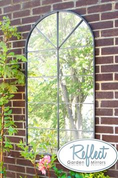 a mirror sitting on the side of a brick wall next to a potted plant