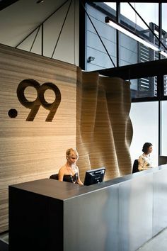 a woman sitting at a desk in front of a sign with the number 99 on it