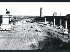 an old black and white photo of a city street with tall buildings in the background