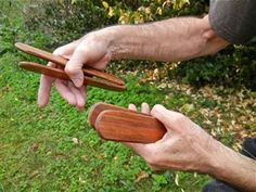 two hands holding wooden objects in the grass